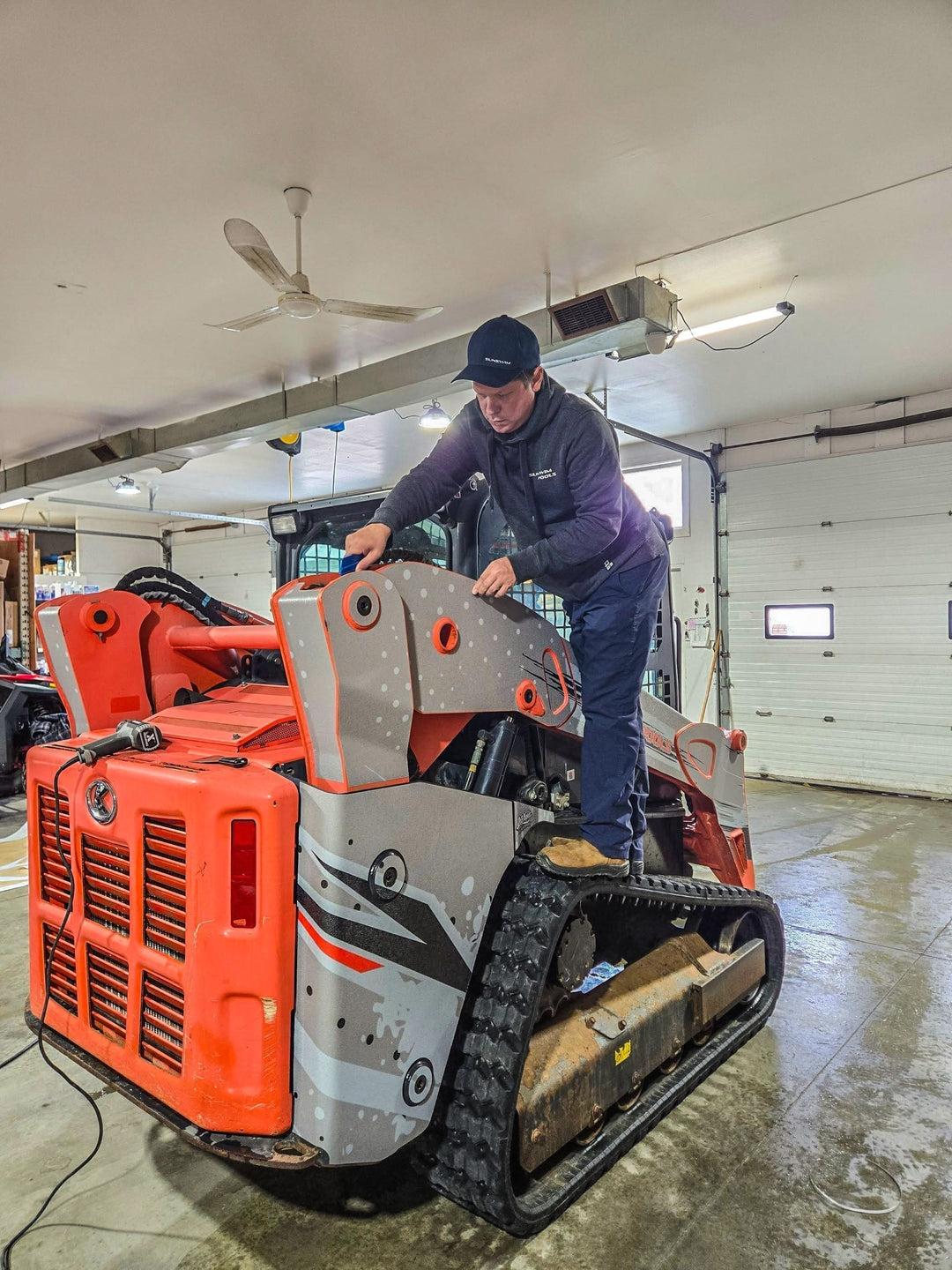 Custom Dirty Graphix wrap being applied to a Kubota mini skid