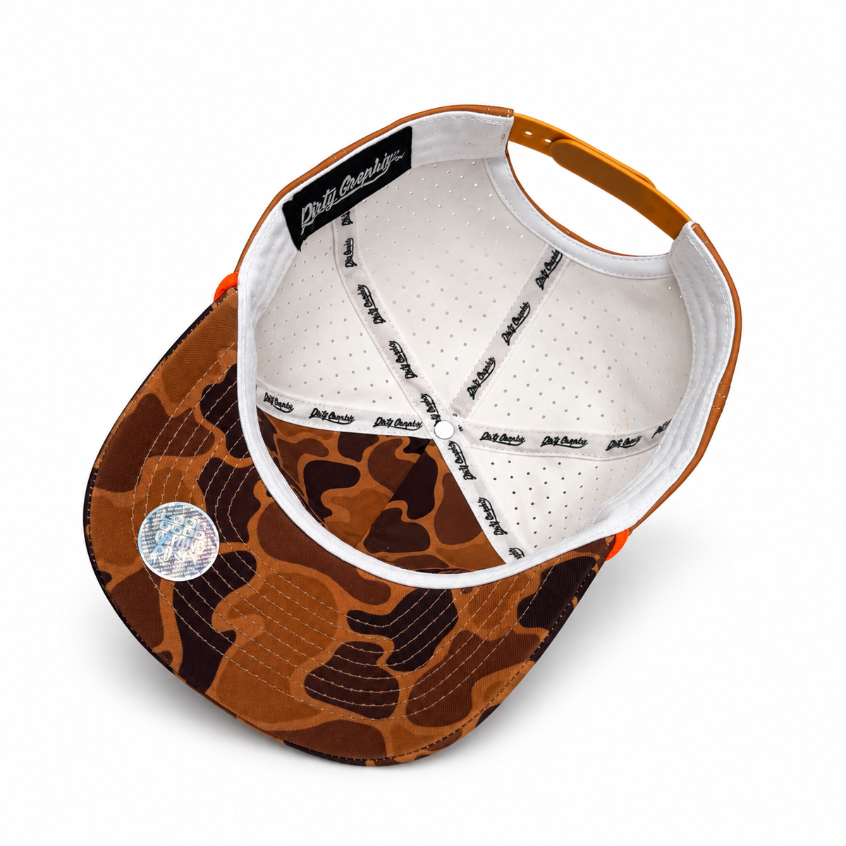 A brown duck camouflage baseball cap shown from a top-down angle, featuring a white interior with printed text and a metallic holographic sticker on the brim.